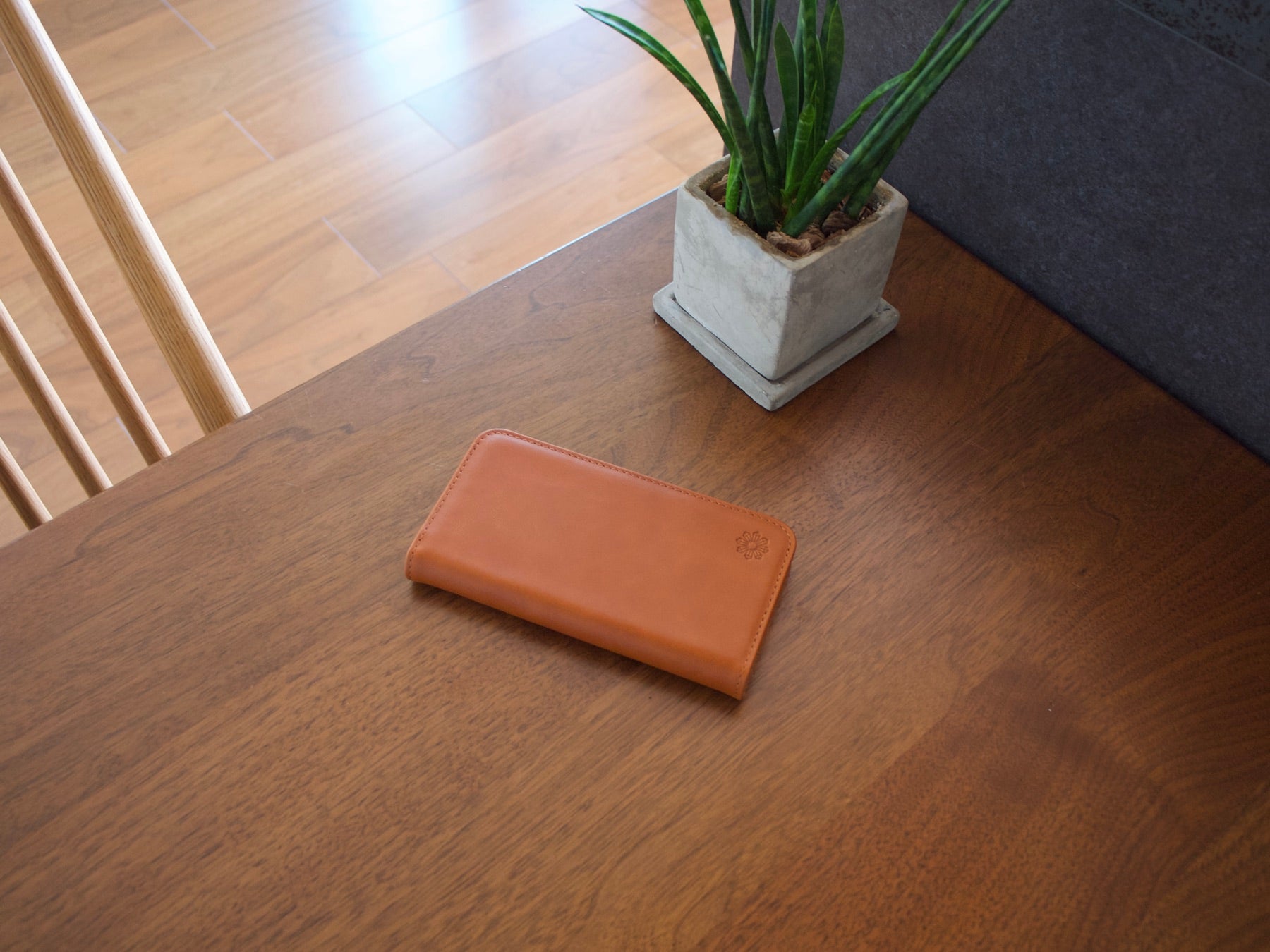 木のテーブルに置かれた、キャメル色の牛革の手帳型スマホケース